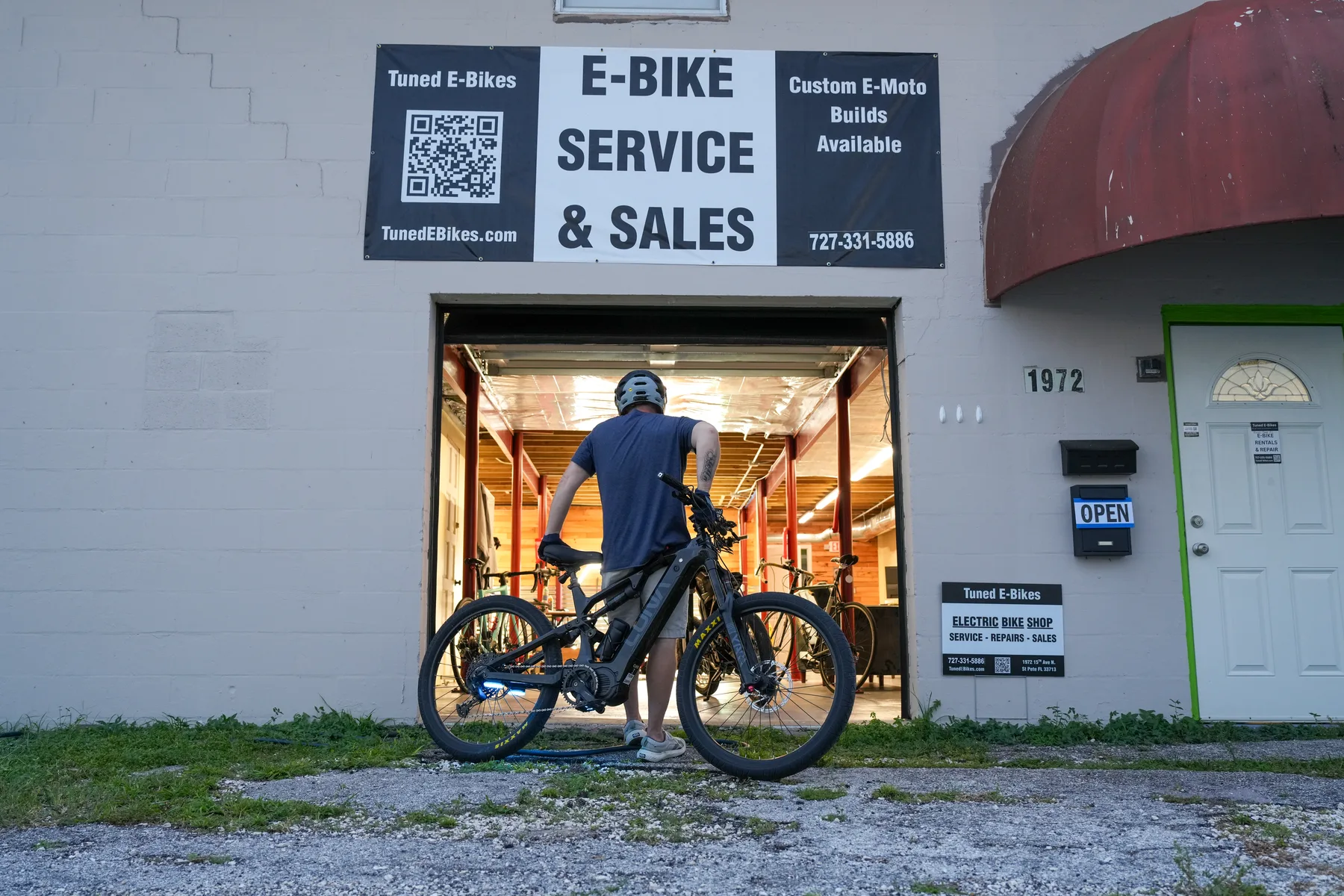 A person with an e-bike outside the Tuned E-Bikes shop entrance