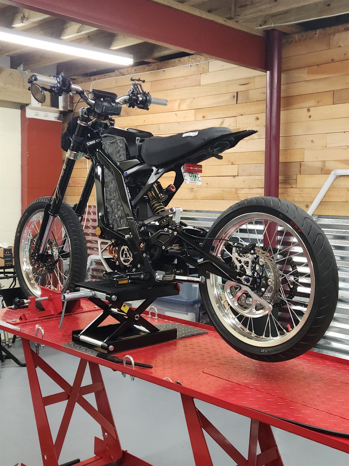 Custom black e-moto up on the lift at the Tuned E-Bikes shop