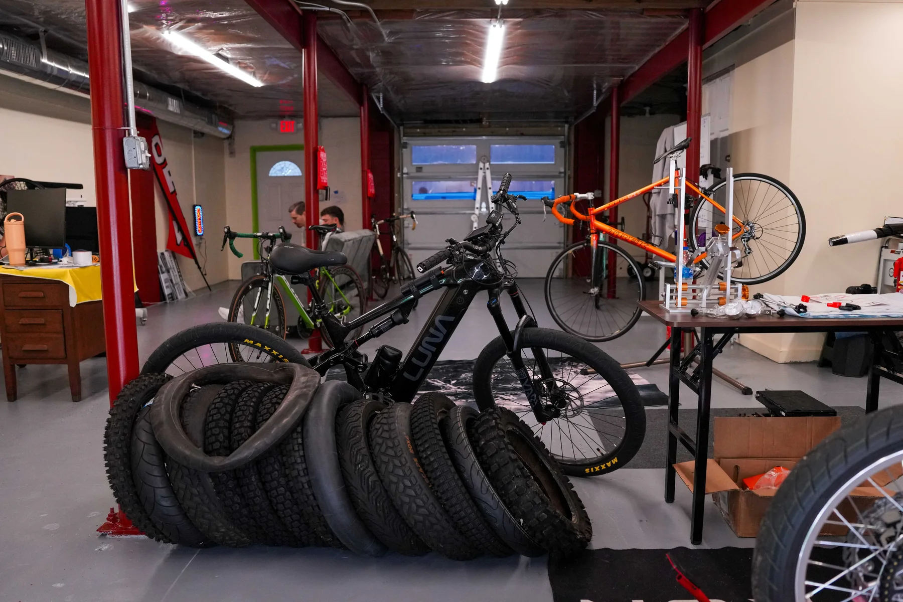 Inside the Tuned E-Bikes shop, with bikes on the workbench and tires ready for service
